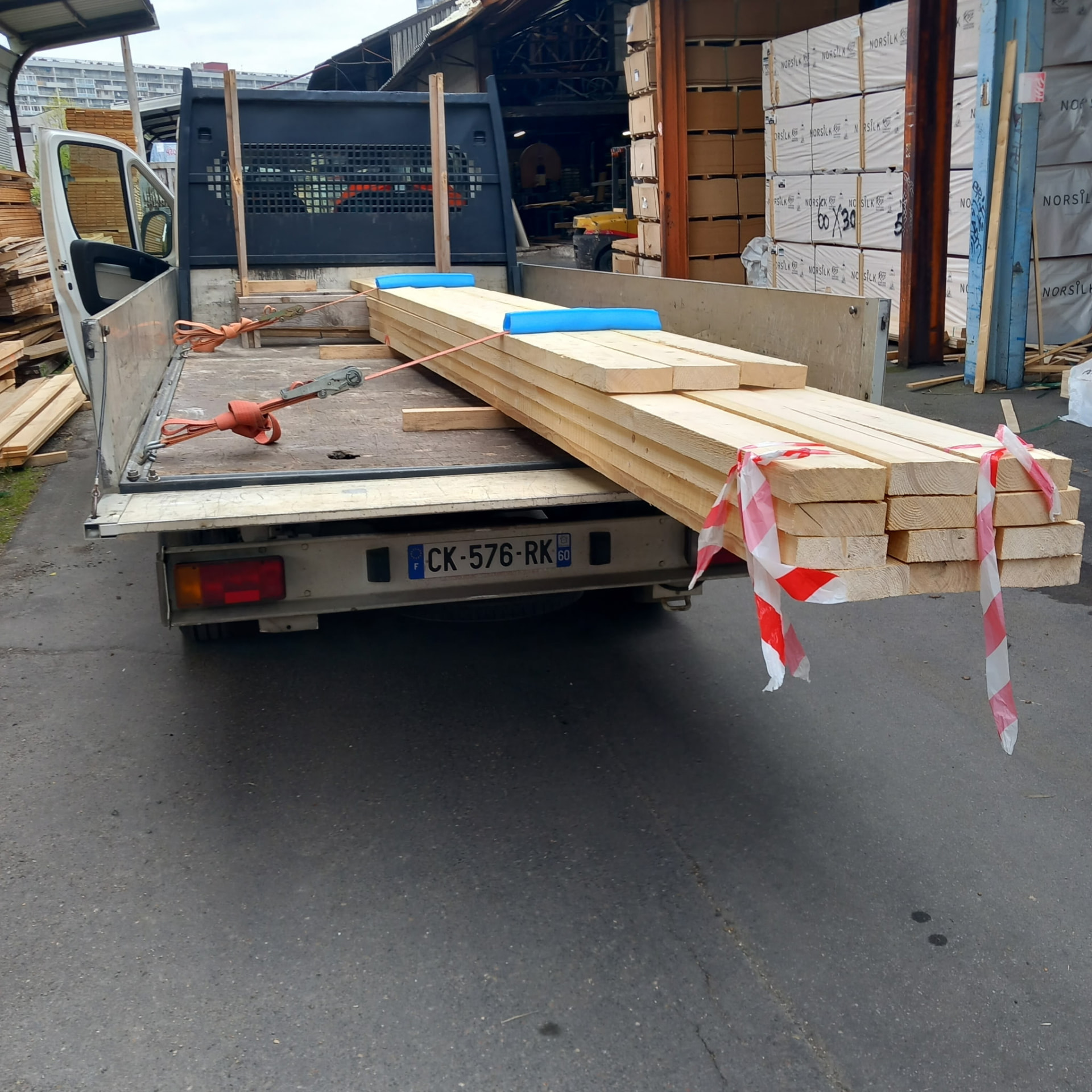 Bois de charpente long transporté en plateau-ridelles